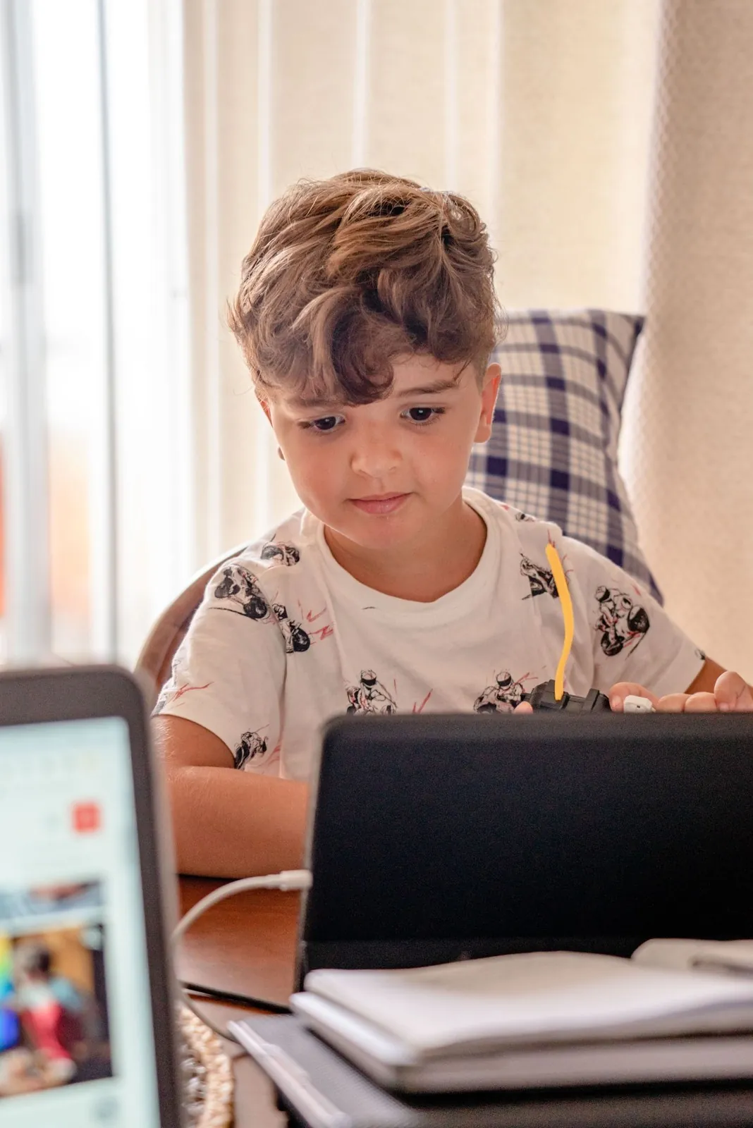 Niño frente a su computador portátil en la casa, atento a una clase online