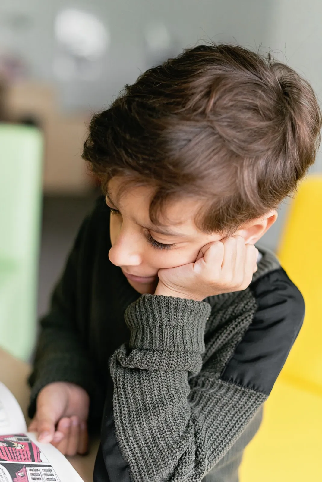 Niño apoya la cara en la mano mientras piensa frente a su libro